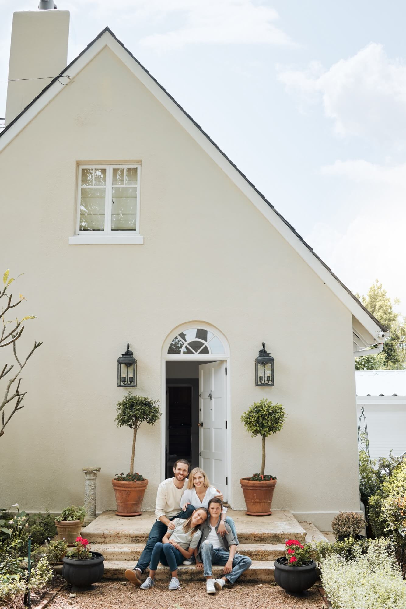 Familj sitter framför sitt hus med ljus putsfasad efter fasadrenovering.