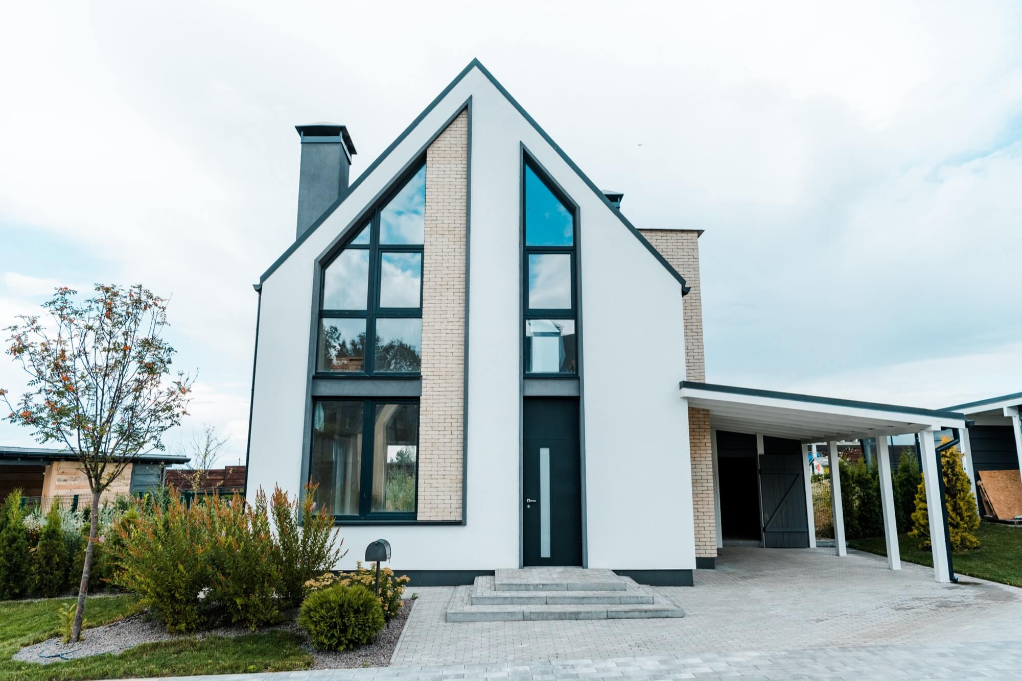Nyrenoverad fasad på modernt hus med stora fönster och putsad yta.
