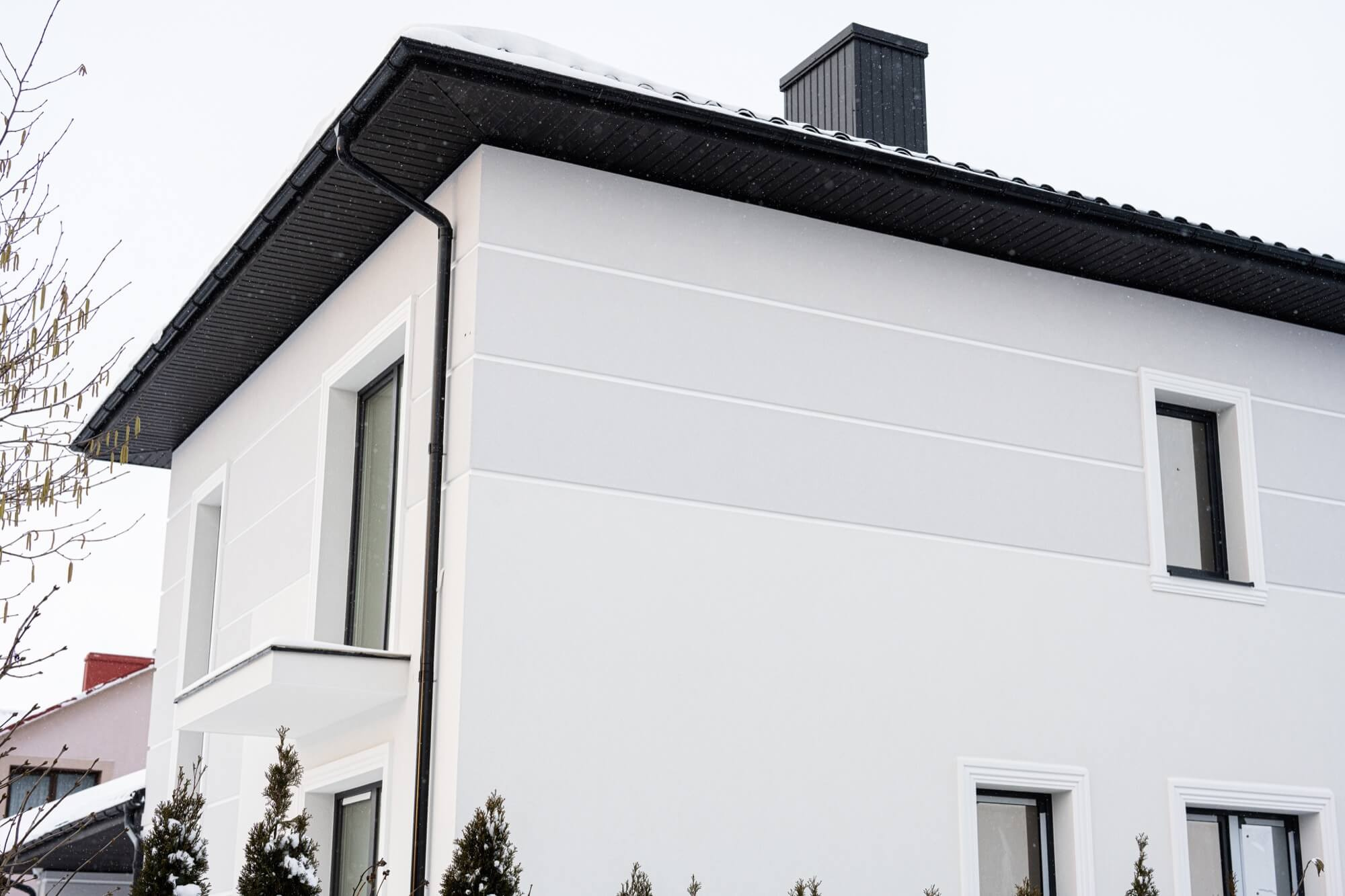 Tvåplanshus med vit putsfasad under vintern, resultat av fasadrenovering.